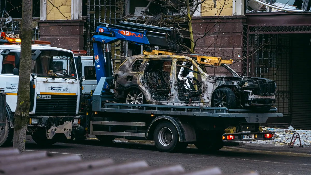 Voiture brûlée remorquée dans une rue